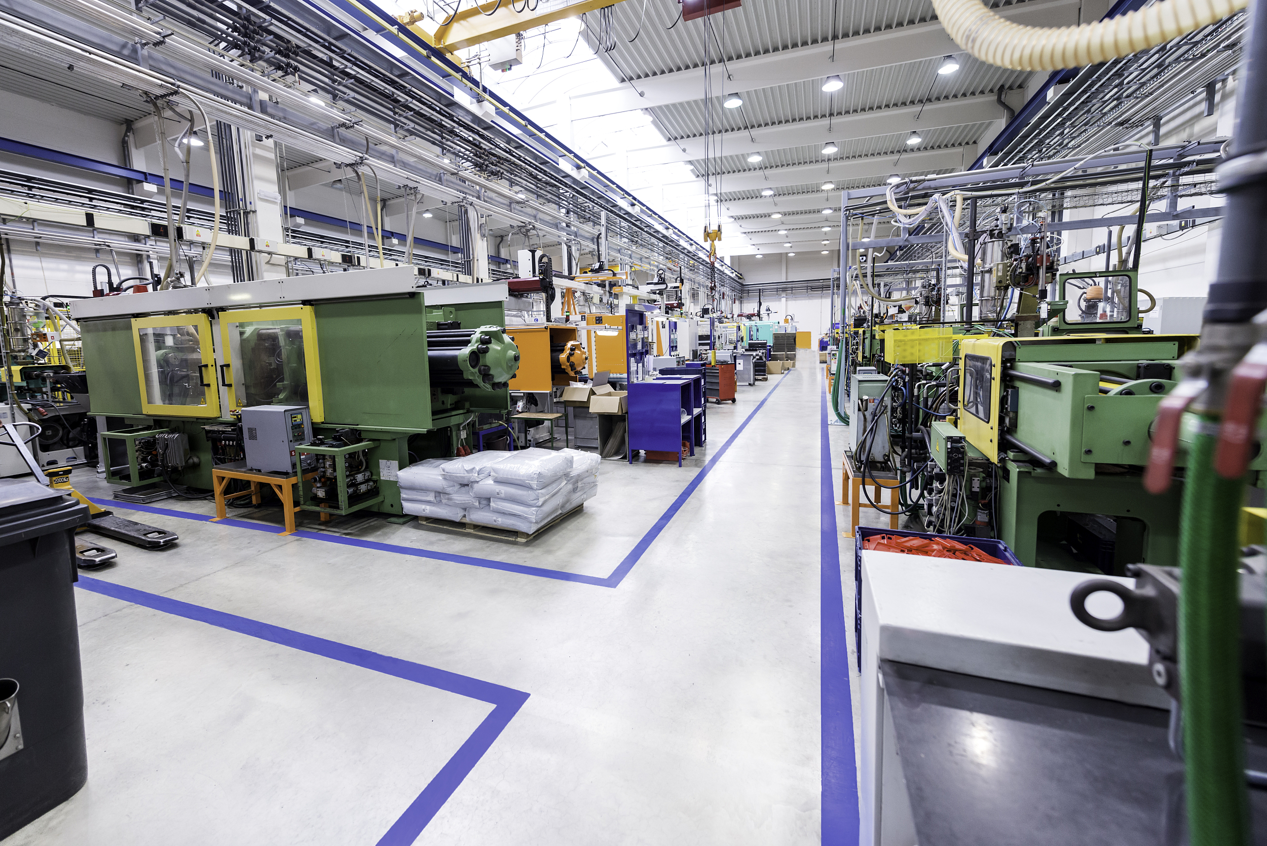 Intérieur spacieux d'une usine moderne de fabrication montrant des rangées de machines de moulage par injection et de découpe laser en activité.