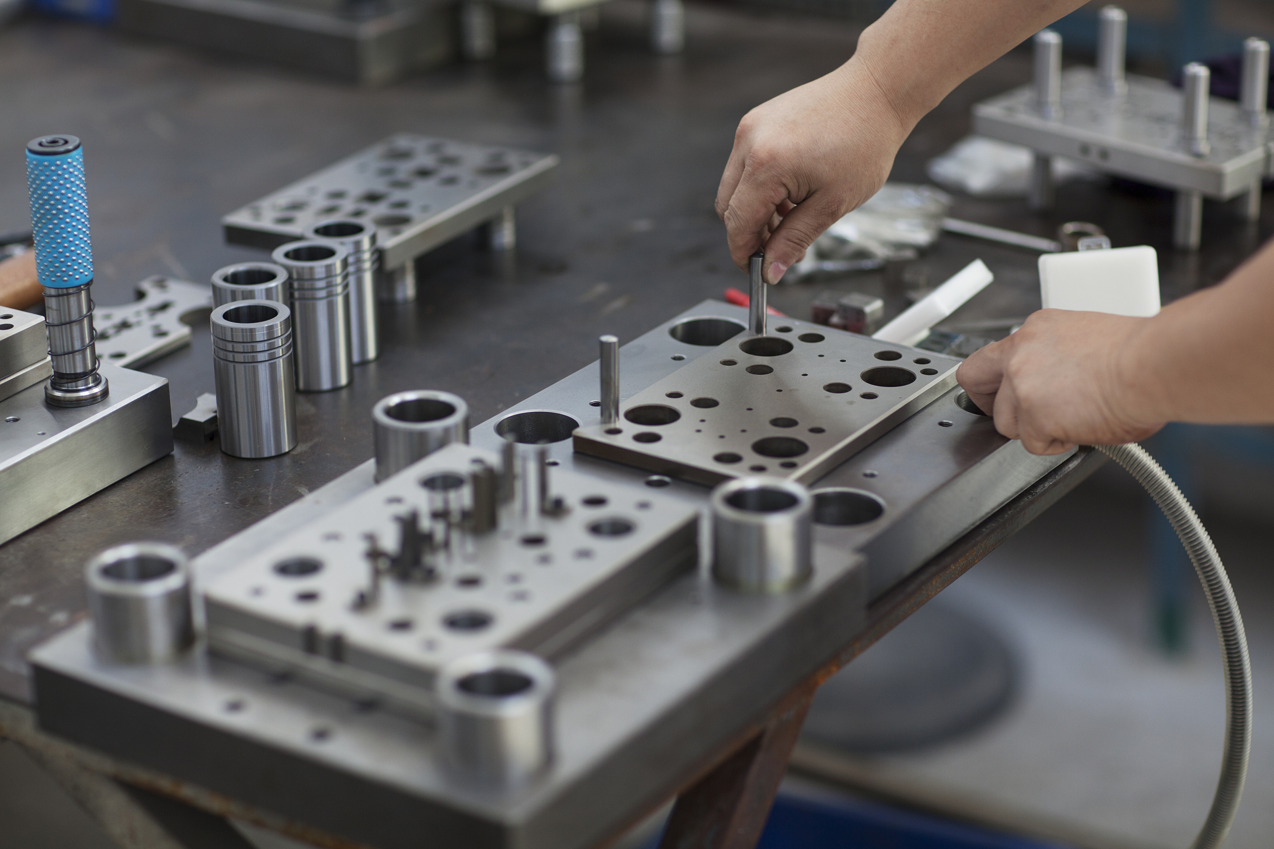 Travailleur ajustant des moules de précision pour l'injection plastique dans un atelier industriel, mettant en évidence des compétences en fabrication métallique sur mesure.