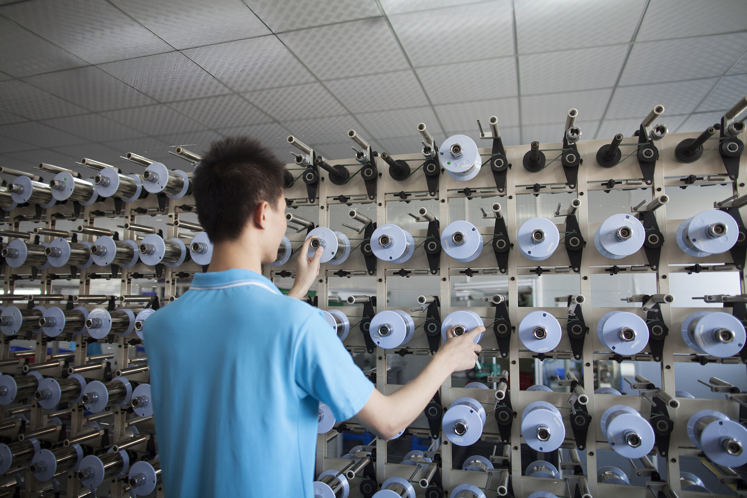 Opérateur surveillant des bobines de fils dans une usine textile en Chine